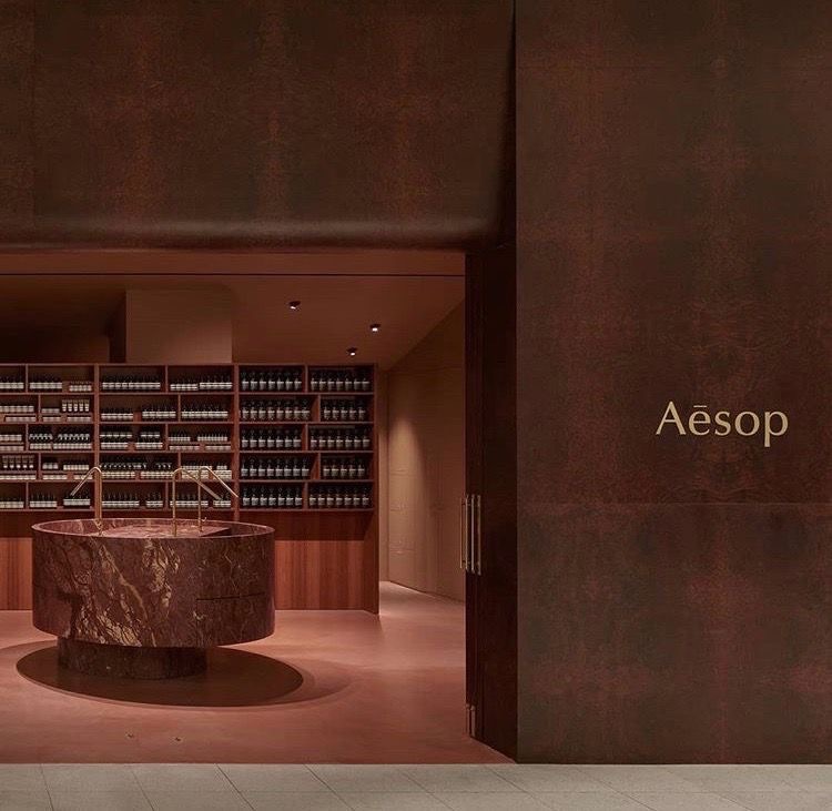 Вход в бутик Aesop с круглой раковиной из красного мрамора