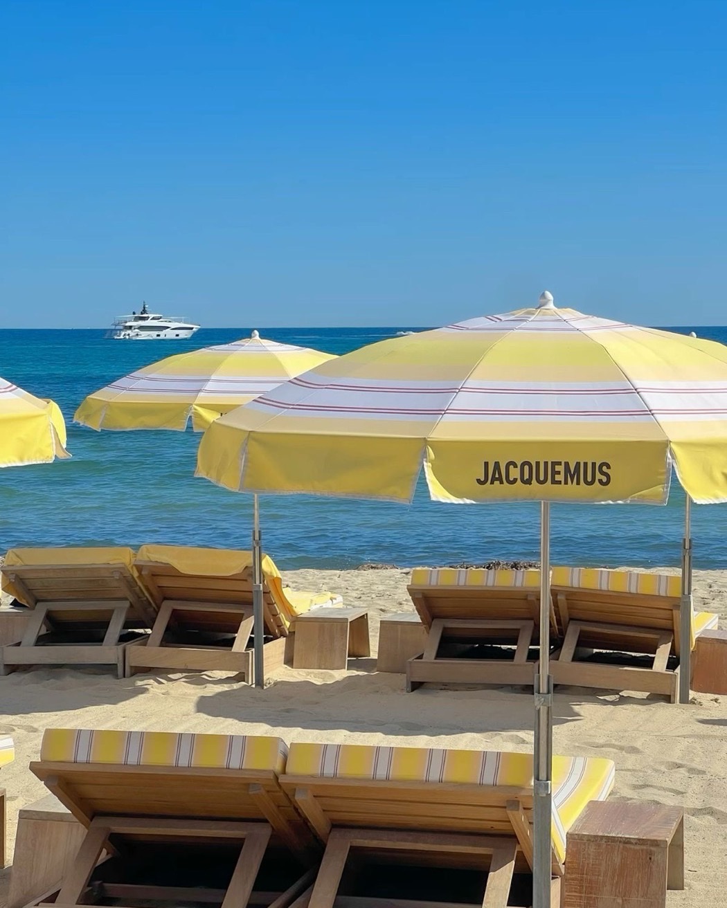 Жёлтые полосатые пляжные зонты Jacquemus на берегу моря